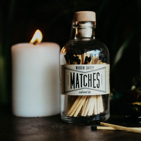 black matches in jar next to lit candle