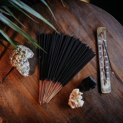 stack of incense next to stick of burning incense