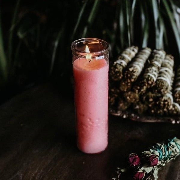 pink 7 day candle next to herb bundle