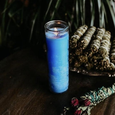 blue 7 day candle next to herb bundle