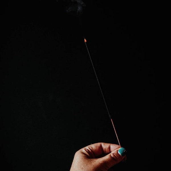 person holding burning incense 